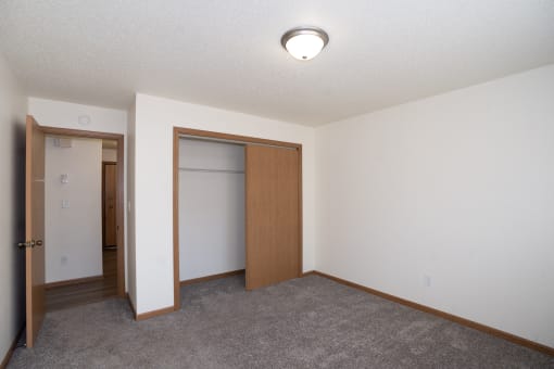 an empty room with a closet and a door to a bathroom. Fargo, ND Country Club Apartments