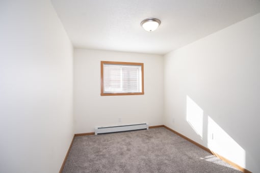 an empty room with carpet and a window. Fargo, ND Country Club Apartments