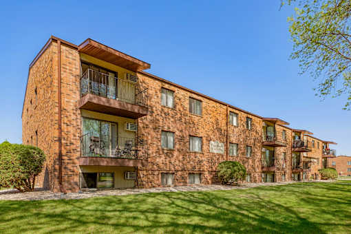 a brick apartment building with green grass and a blue sky