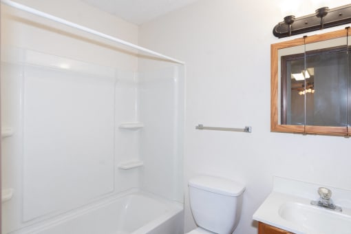 a small bathroom with a toilet sink and shower. Fargo, ND Hartford Apartments