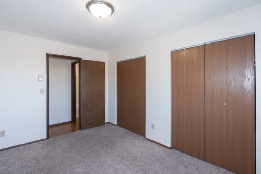 an empty room with three doors and a door to a closet. Fargo, ND Hartford Apartments