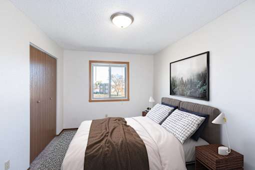 a bedroom with a bed and a window. Fargo, ND Hartford Apartments