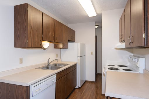 an empty kitchen with white appliances and wooden cabinets. Fargo, ND Hartford Apartments