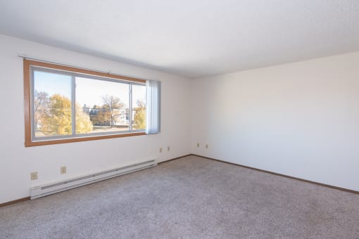 the living room of an empty house with a large window. Fargo, ND Hartford Apartments