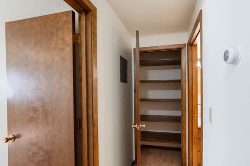 a wooden door opens to a hallway with a staircase and a door to a bathroom. Fargo, ND Hawn Apartments