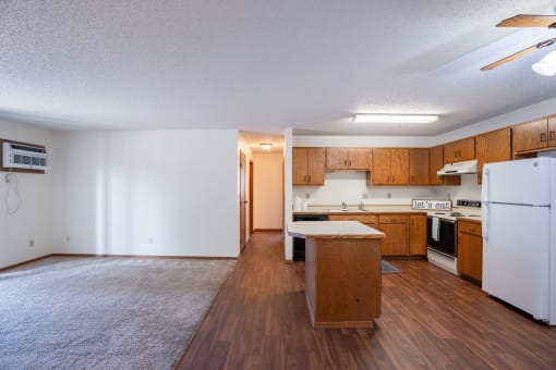 a kitchen and living room with white appliances. Fargo, ND Kentwood Manor Apartments