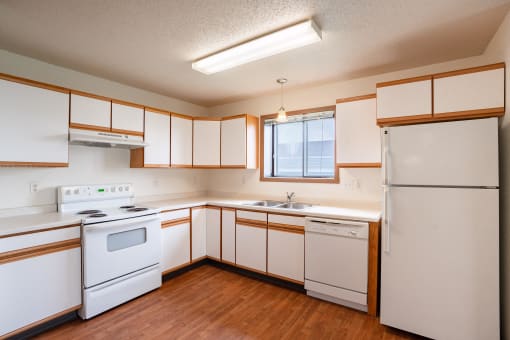 an empty kitchen with white appliances and white cabinets. West Fargo, ND Lake Crest Apartments
