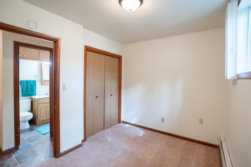 an empty room with a door to a bathroom and a toilet. Fargo, ND Luxford Apartments