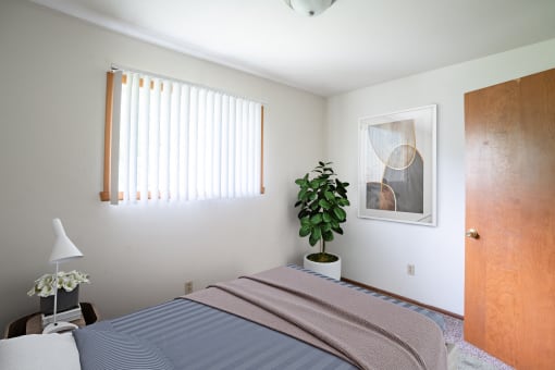 a bedroom with a bed and a plant. Fargo, ND Luxford Apartments