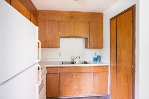 a small kitchen with wooden cabinets and a white refrigerator. Fargo, ND Luxford Apartments