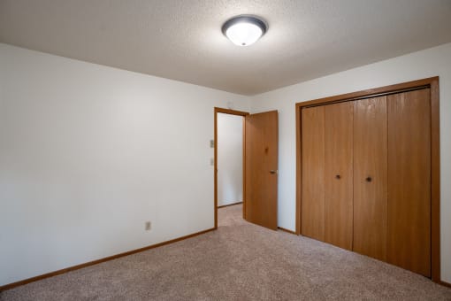 a bedroom with carpet and a door to a closet. Fargo, ND Monticello Apartments