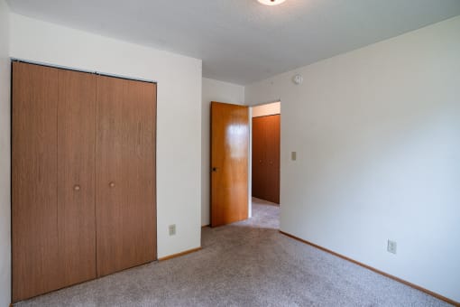 an empty living room with a door to a hallway and a closet. Fargo, ND Morningside Apartments