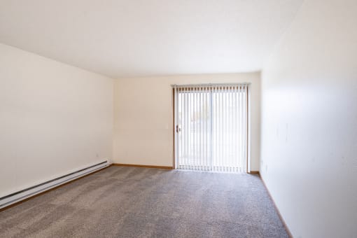 the spacious living room of an apartment with a door to the balcony. Fargo, ND Oxford Apartments