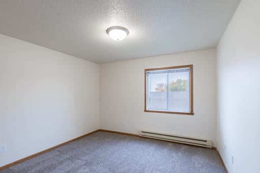the living room of an empty house with a window. Fargo, ND Oxford Apartments