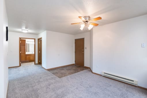the living room and dining room of an empty house with a ceiling fan. Fargo, ND Oxford Apartments