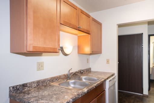 a kitchen with wood cabinets and granite counter tops and a sink. Fargo, ND Pacific Park 2
