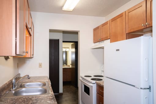 a kitchen with white appliances and wooden cabinets and a refrigerator. Fargo, ND Pacific Park 2