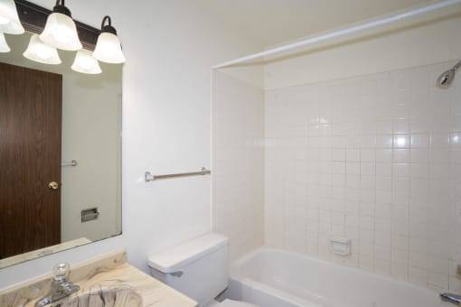 a white bathroom with a tub and a sink and a mirror. Fargo, ND Pacific Park 2