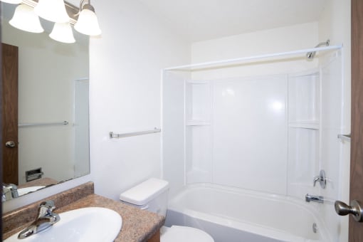 a bathroom with a sink and a tub and a mirror. Fargo, ND Pacific Park Apartments
