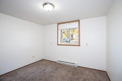 an empty room with carpet and a window. Fargo, ND Pacific Park Apartments