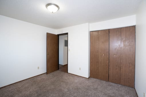 a bedroom with a closet and a door to a hallway. Fargo, ND Pacific Park Apartments