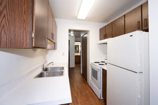 a kitchen with white appliances and wooden cabinets and a white refrigerator. Fargo, ND Pacific Park Apartments