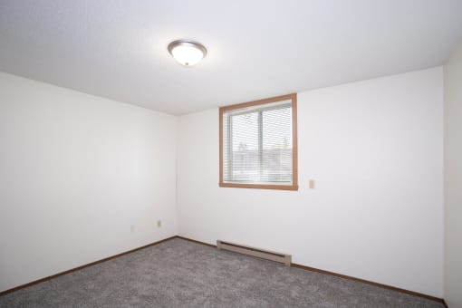 an empty room with a window and carpet. Fargo, ND Pacific Park Apartments