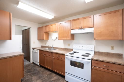 a kitchen with wood cabinets and white appliances. Fargo, ND Pacific Park Apartments