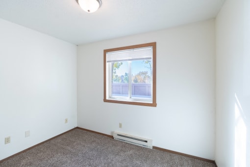 the living room of an empty house with a window. Fargo, ND Pacific Park Apartments