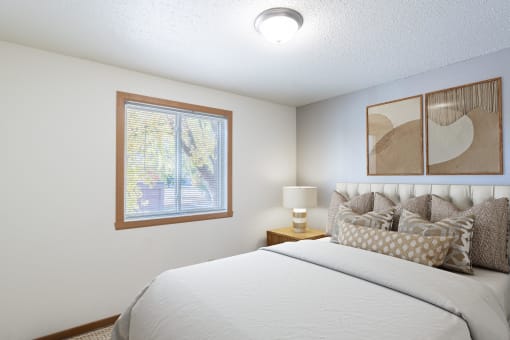 a bedroom with a large bed and a window. Fargo, ND Pacific Park Apartments