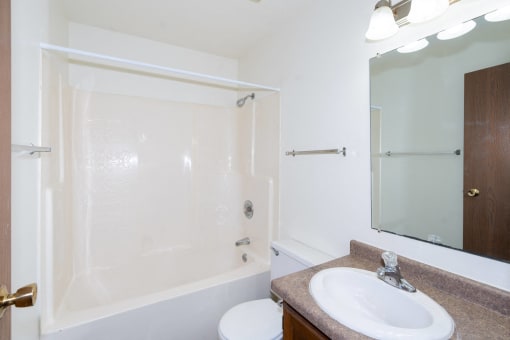 a bathroom with a sink and a shower and a mirror. Fargo, ND Pacific South Apartments