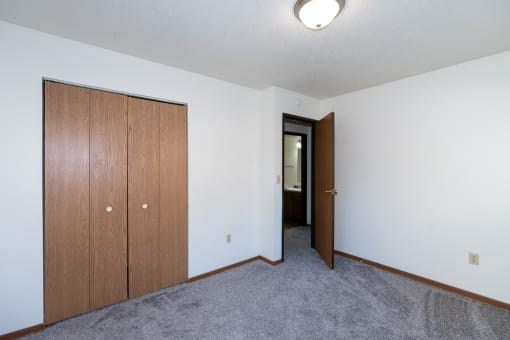 a bedroom with a closet and carpeted floors. Fargo, ND Pacific South Apartments