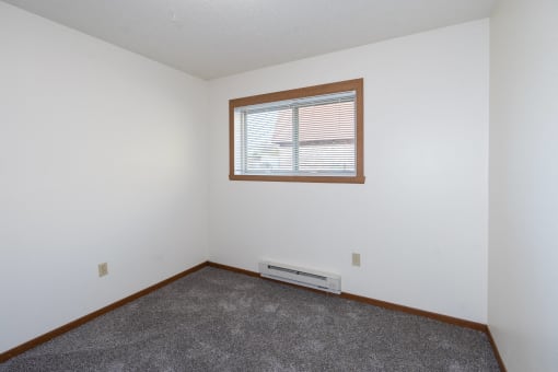 an empty room with a window and carpet. Fargo, ND Pacific South Apartments