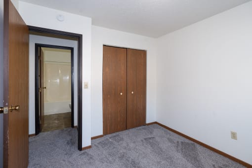 an empty room with a closet and a door to a bathroom. Fargo, ND Pacific South Apartments