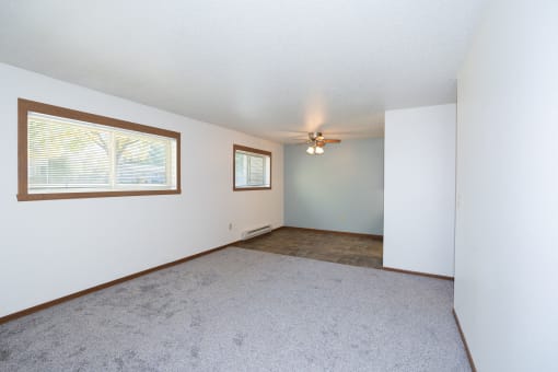 an empty living room with a ceiling fan and a window. Fargo, ND Pacific South Apartments