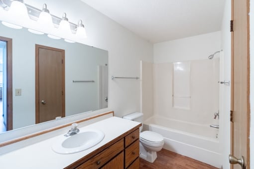 a bathroom with a sink toilet and shower and a mirror. Fargo, ND Rosegate Apartments