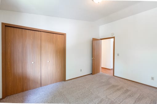 an empty living room with a door to a bedroom and a closet. Fargo, ND Rosegate Apartments
