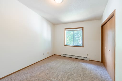 the living room of an empty house with a window. Fargo, ND Rosegate Apartments