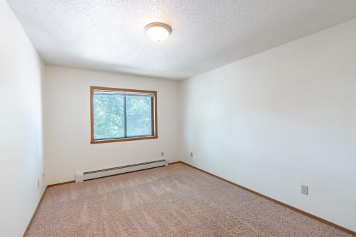 the living room of an empty house with a window. Fargo, ND Rosegate Apartments