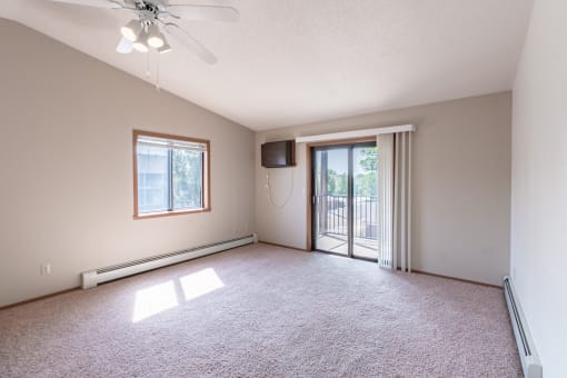 an empty living room with a sliding glass door to a balcony. Fargo, ND Rosegate Apartments