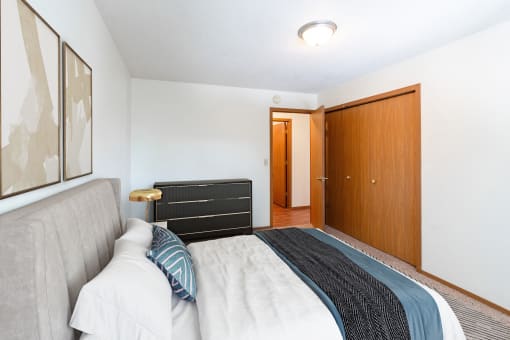 a bedroom with a bed and a closet and a door to a bathroom. Fargo, ND Rosegate Apartments