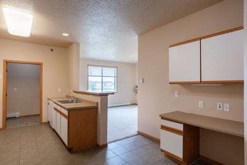 an empty kitchen with a sink and a door to a living room. West Fargo, ND West Lake Apartments 11A | BedroomWest Fargo, ND West Lake Apartments 11A | Kitchen