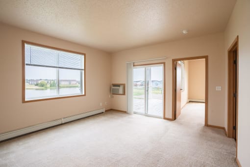 the living room of an empty house with a door and a window. West Fargo, ND West Lake Apartments 11A