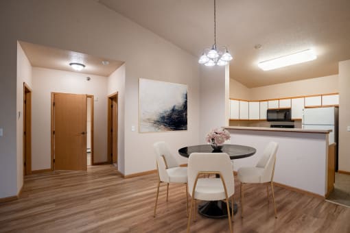 a dining room with a table and chairs and a kitchen. Fargo, ND West Lake Apartments