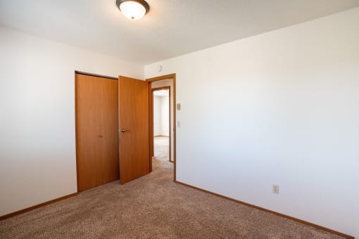 a bedroom with a carpeted floor and a door to a closet. Fargo, ND Westview Towers Apartments