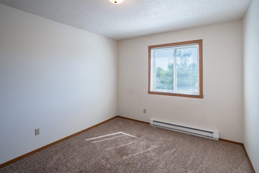 a bedroom with a window and carpeted floors. Fargo, ND Westview Towers Apartments