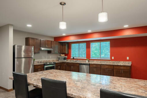 a kitchen with a granite counter top island and stainless steel appliances. Fridley, MN Georgetown on the River Apartments