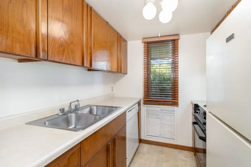 a kitchen with a sink and a refrigerator and wooden cabinets.  Golden Valley, MN Valley View Apartments