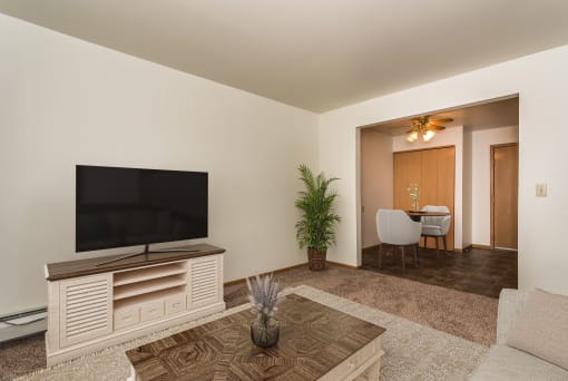 a living room with a tv and a dining room in the background  at Amberwood Court, Grand Forks, ND, 58201