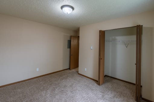 Grand Forks, ND Autumn Apartments. A bedroom with carpeted floors and a closet.